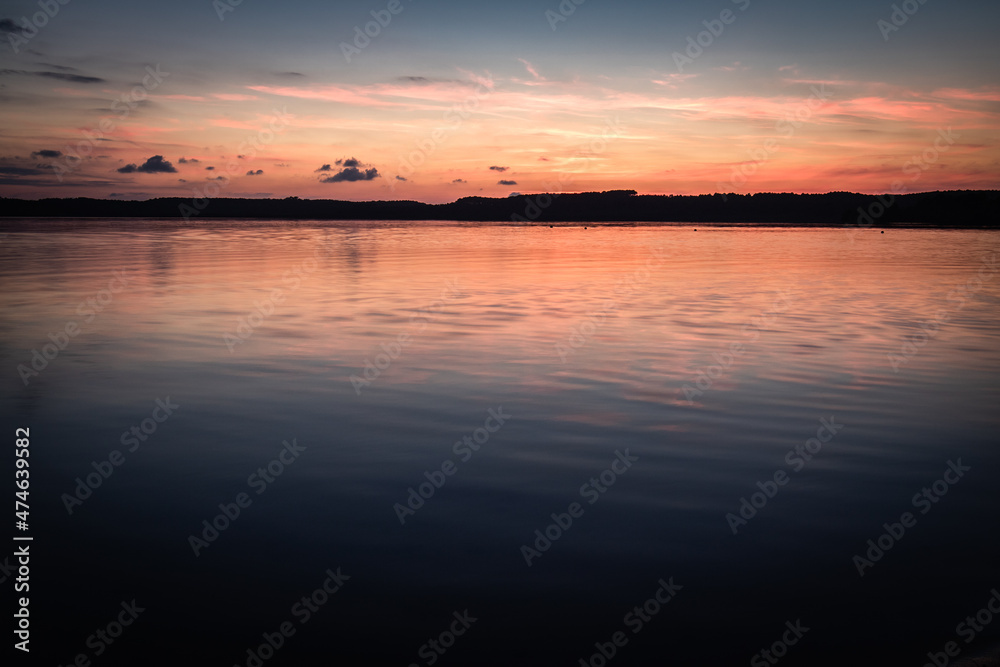 Beautiful sunset on the lake, reflection of clouds and moon, background