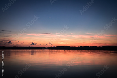 Beautiful sunset on the lake, reflection of clouds and moon, background