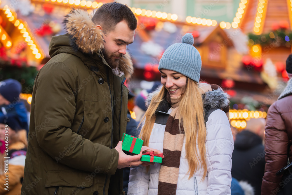 Beautiful couple, boyfriend give a present gift box to a girlfriend  on Christmas fair in Wroclaw, Poland
