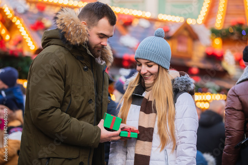 Beautiful couple, boyfriend give a present gift box to a girlfriend on Christmas fair in Wroclaw, Poland