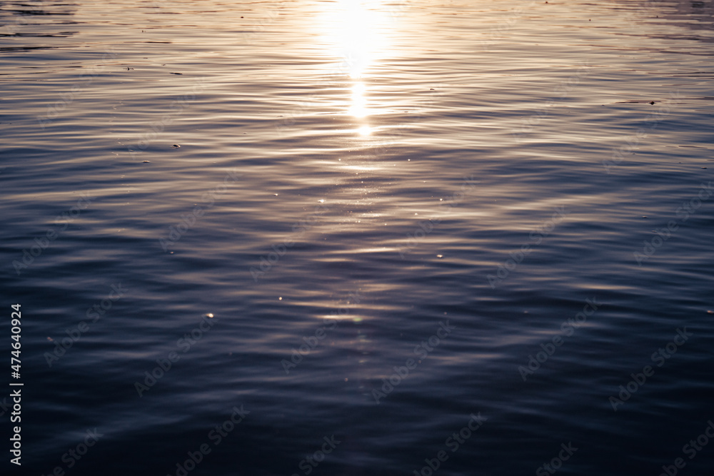 close up of wavy water surface with sun reflection