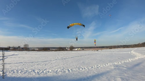 Skydiving. Tandem is landing on the snowy field.