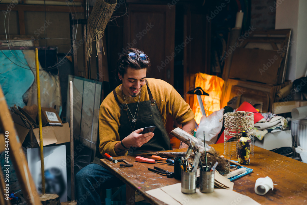 man using smartphone in his workshop man using smartphone in his workshop