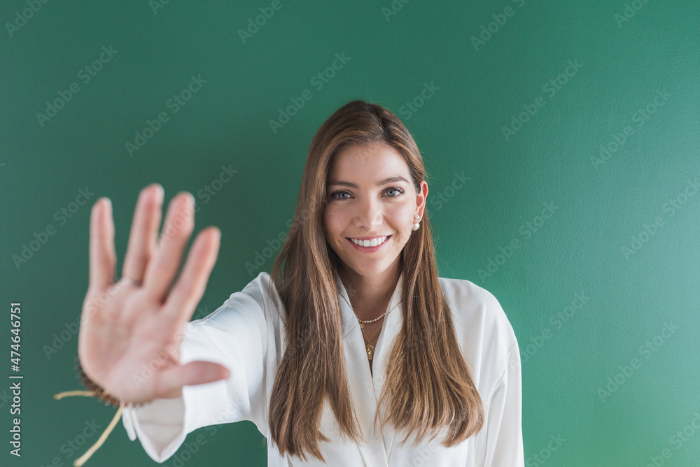 Smiling woman showing stop hand sign against green background Smiling woman showing stop hand sign against green background