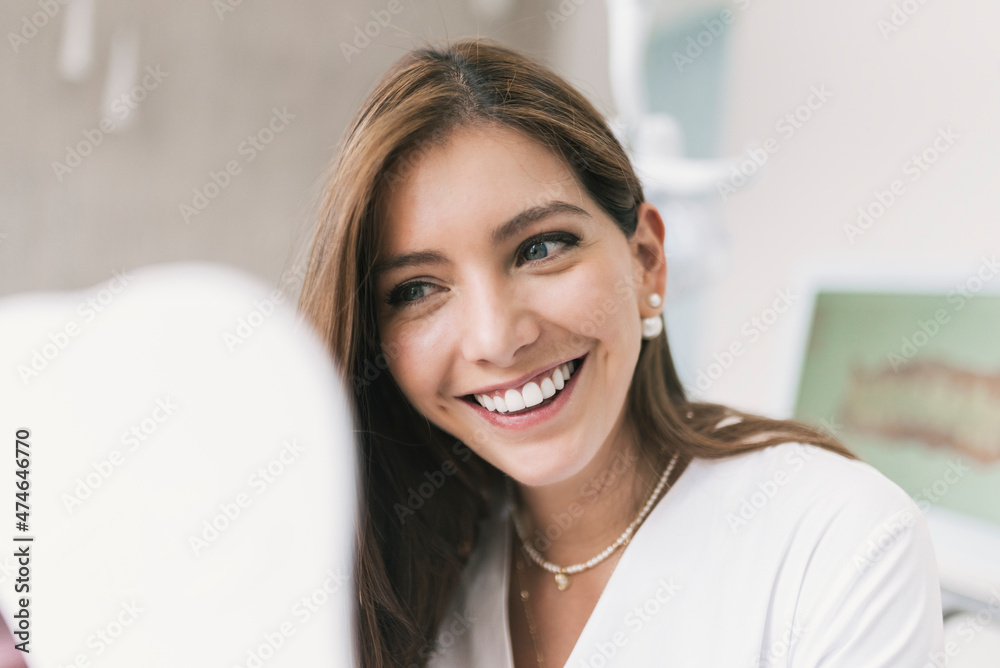 Happy woman looking at mirror at dentist's clinic Happy woman looking at mirror at dentist's clinic