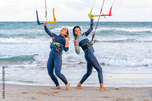 Cheerful friends gesturing and kitesurfing at beach photo