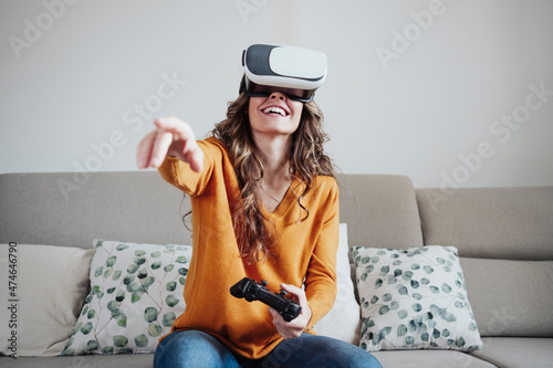 Woman with joystick gesturing wearing virtual reality headset at home photo