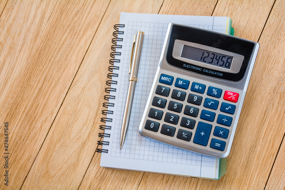 Calculator and notebook with pen on a wooden table Calculator and notebook with pen on a wooden table
