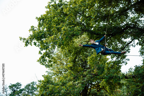 Businessman tied up with rope hanging on tree showing fist
