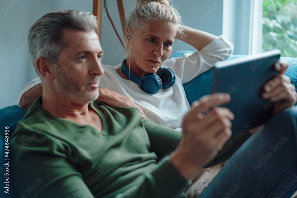 Couple using tablet PC on sofa in living room Couple using tablet PC on sofa in living room