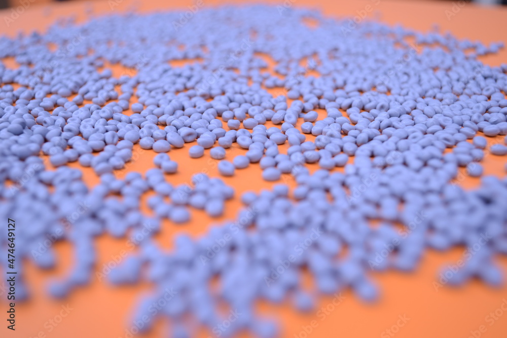 Grey polymer granules on orange background Grey polymer granules on orange background
