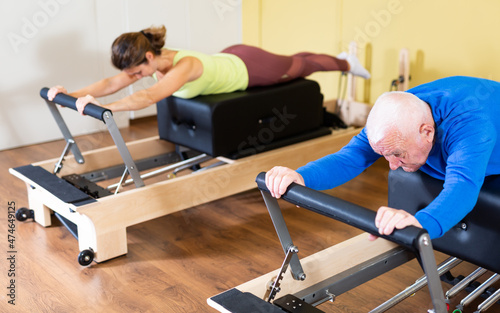 Elderly man doing exercises at physiotherapy clinic - revitalizing gym exercises