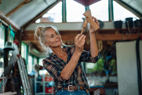 Woman holding wooden tool at garden shed photo