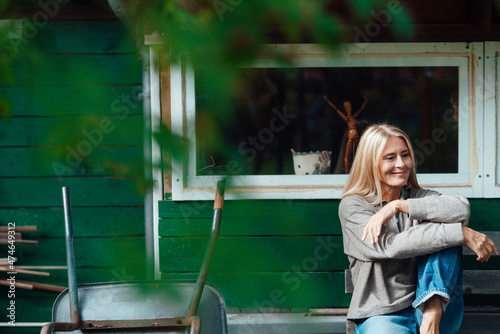 Smiling woman sitting on bench at garden shed photo