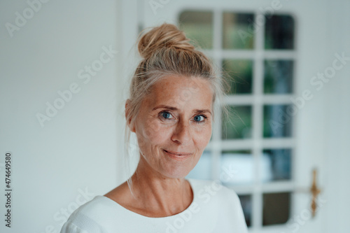 Smiling woman with hair bun at home