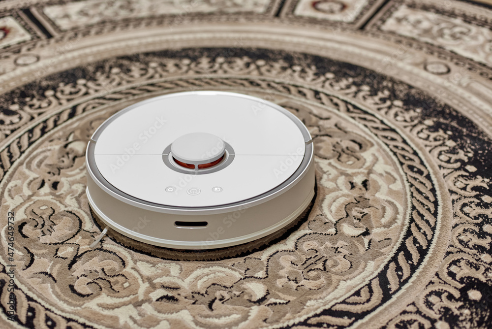 White robot vacuum cleaner isolated on beige carpet
