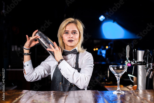 Girl bartender creates a cocktail on the saloon photo