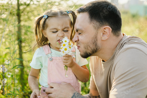 Playful father and daughter smelling daisies photo