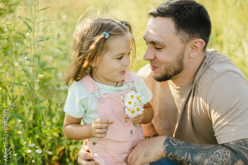 Smiling father looking at daughter holding daisies