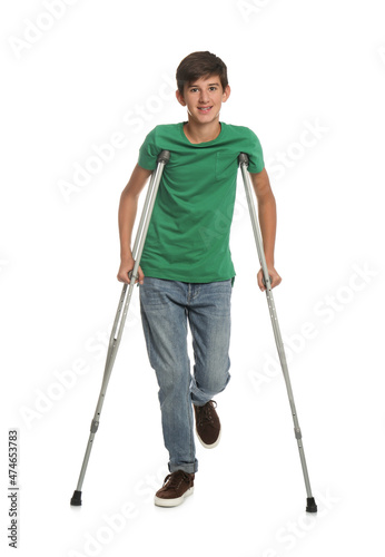Teenage boy with injured leg using crutches on white background © New Africa