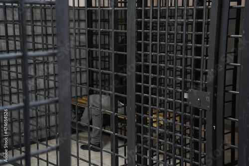 The grating of the temporary detention cell in which the detainee is sitting