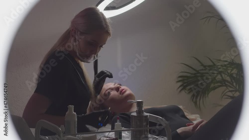 Two girls in a beauty salon do makeup with a permanent
