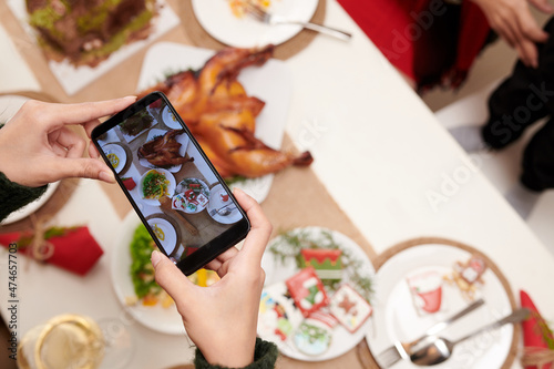 Hands of person taking photo of Christmas dinner to upload on social media © DragonImages