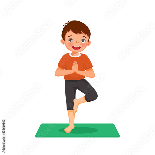 Little boy doing yoga pose on a green mat at home 