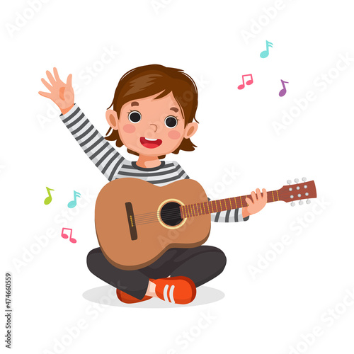 Little girl playing guitar sitting on floor waving hand with smiling facial expression