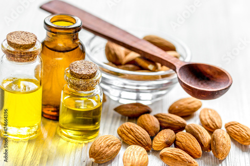 cosmetic and therapeutic almond oil on light wooden background
