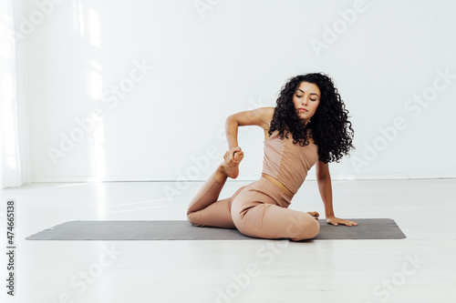 woman doing yoga asana gymnastics exercises in a white hall