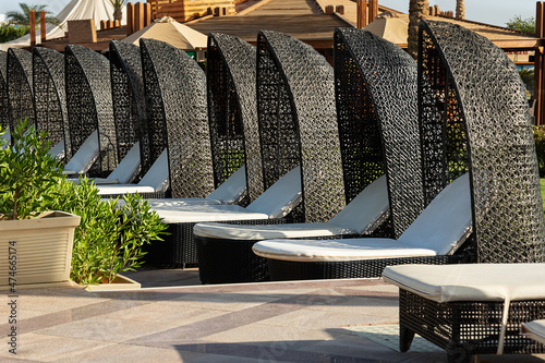 Fotografia, Obraz row of empty sun loungers with soft white mattresses and rattan canopy