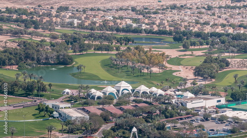 Canvas Print Aerial view to Golf course with green lawn and lakes, villa houses behind it timelapse