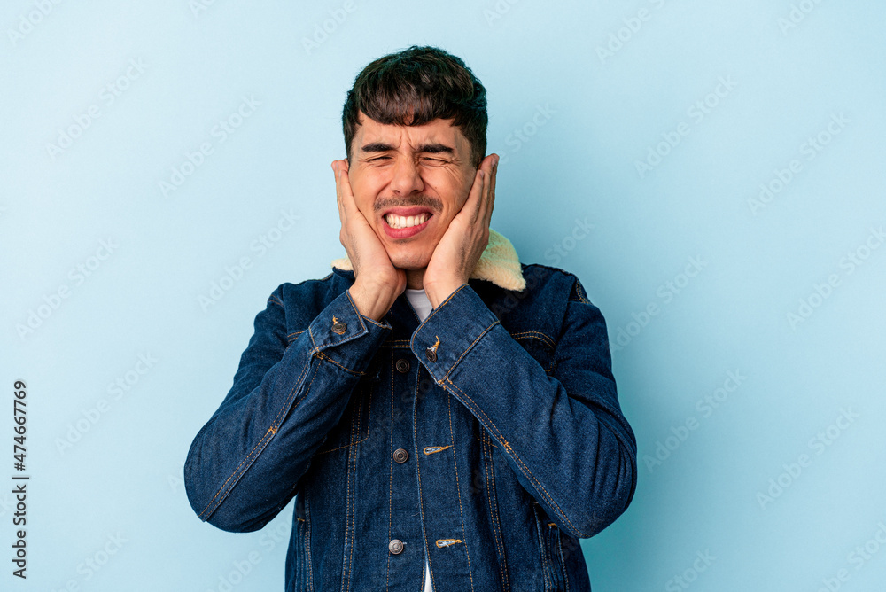 Young mixed race man isolated on blue background covering ears with hands. Young mixed race man isolated on blue background covering ears with hands.