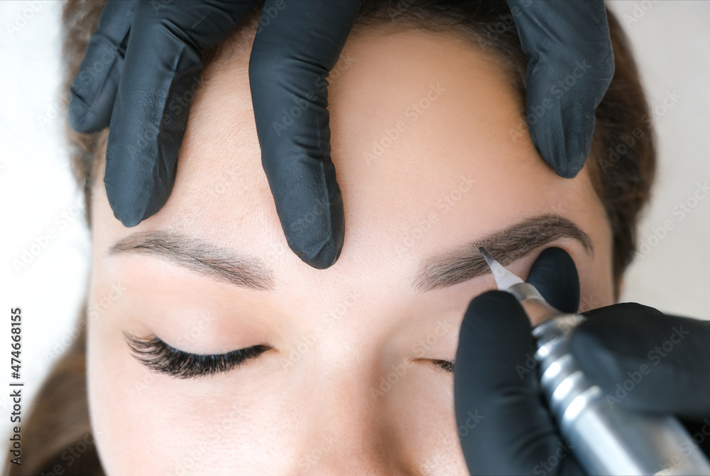 Beautician makes permanent eyebrow makeup on the face of a beautiful young woman. Beautician makes permanent eyebrow makeup on the face of a beautiful young woman.