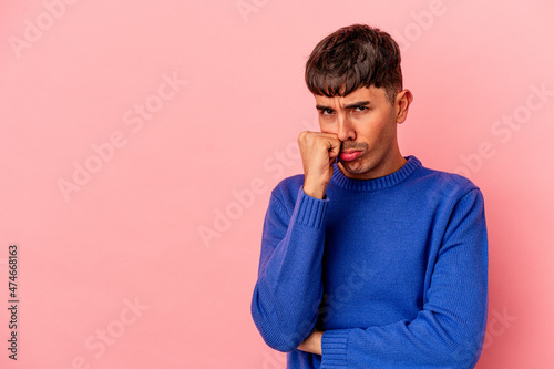 Young mixed race man isolated on pink background who feels sad and pensive, looking at copy space. © Asier
