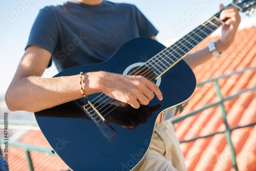 Close-up of black acoustic guitar. Man playing guitar, hands on strings. Party, music, hobby concept