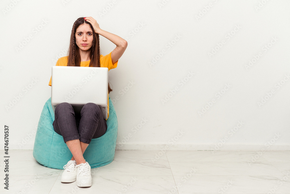 Young caucasian woman working with laptop sitting on a puff isolated on white background being shocked, she has remembered important meeting. Young caucasian woman working with laptop sitting on a puff isolated on white background being shocked, she has remembered important meeting.