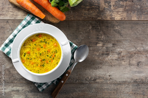 Chicken noodle soup in white bowl on wooden table.Top view. Copy space photo