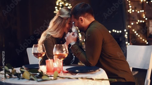 Holding each other by the hands. Sweet lovely couple having a romantic dinner indoors together