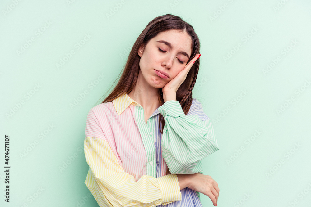 Young caucasian woman isolated on green background who is bored, fatigued and need a relax day.