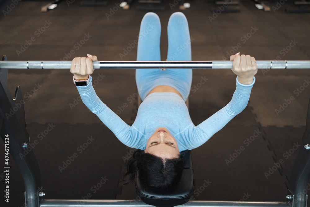 Woman lifts a barbell while lying on a bench Woman lifts a barbell while lying on a bench