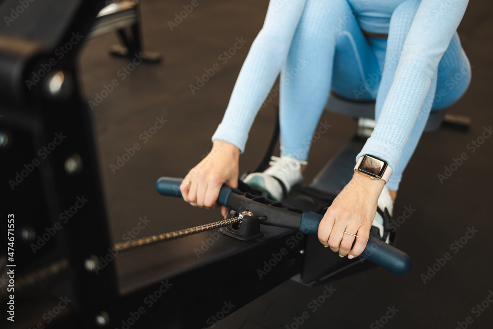 Woman in blue sportswear working out on a rowing machine Woman in blue sportswear working out on a rowing machine