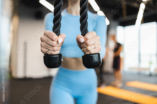 Woman doing pushdowns with rope for triceps at the gym closeup