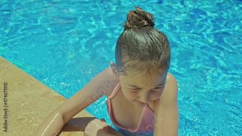 Little girl having fun in swimming pool.Happy cute little girl enjoying hot summer day at resort, having fun and smiling at camera.
