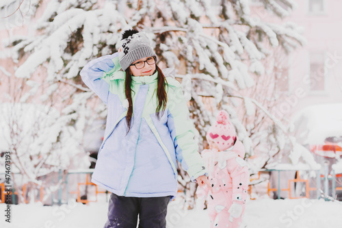 Little girl having fun in snowy yard. Happy kid playing with snow