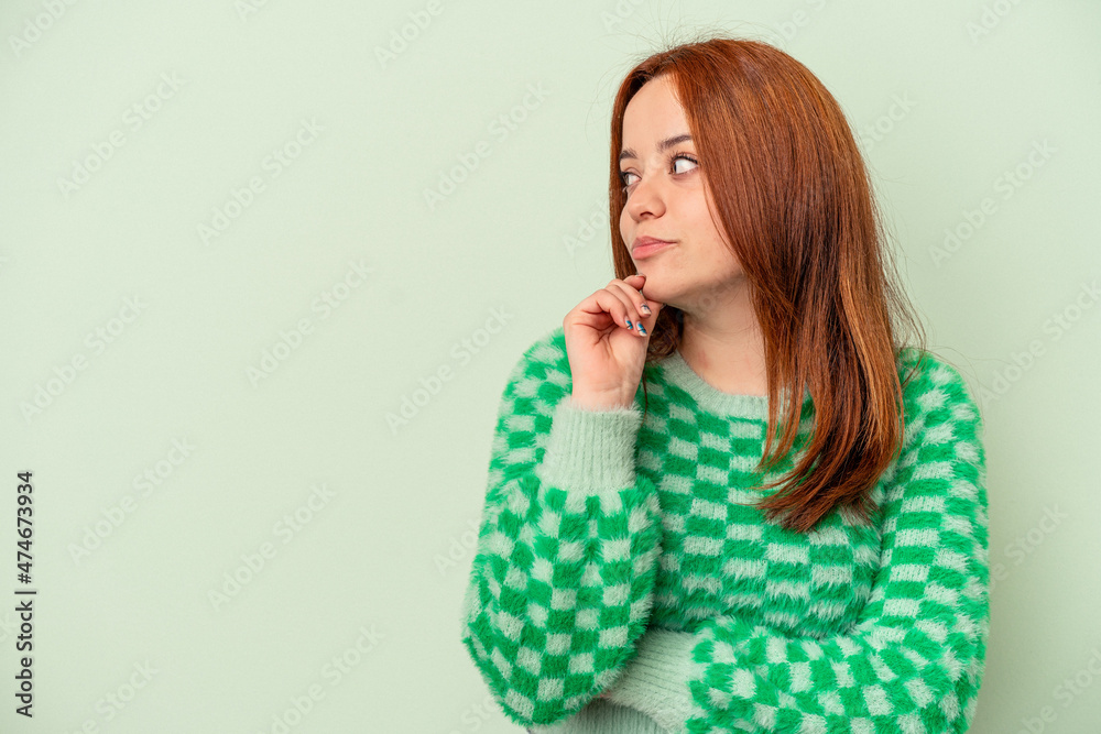 Young caucasian woman isolated on green background looking sideways with doubtful and skeptical expression. Young caucasian woman isolated on green background looking sideways with doubtful and skeptical expression.