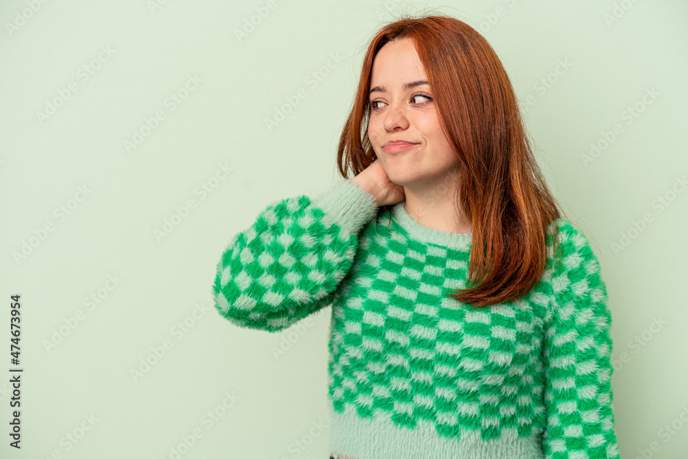 Young caucasian woman isolated on green background touching back of head, thinking and making a choice. Young caucasian woman isolated on green background touching back of head, thinking and making a choice.