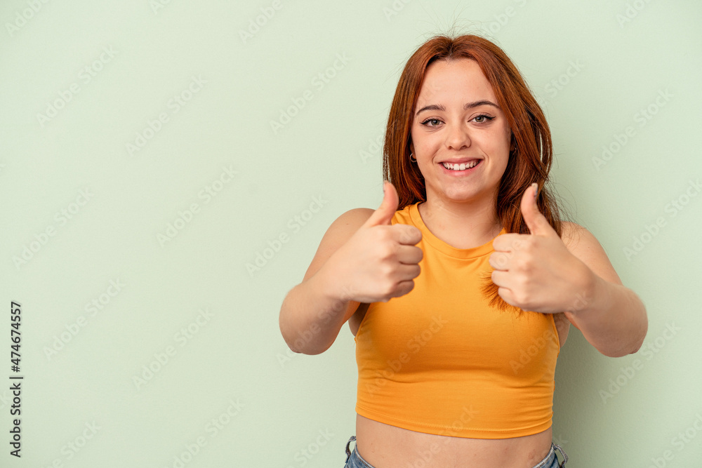 Young caucasian woman isolated on green background smiling and raising thumb up Young caucasian woman isolated on green background smiling and raising thumb up
