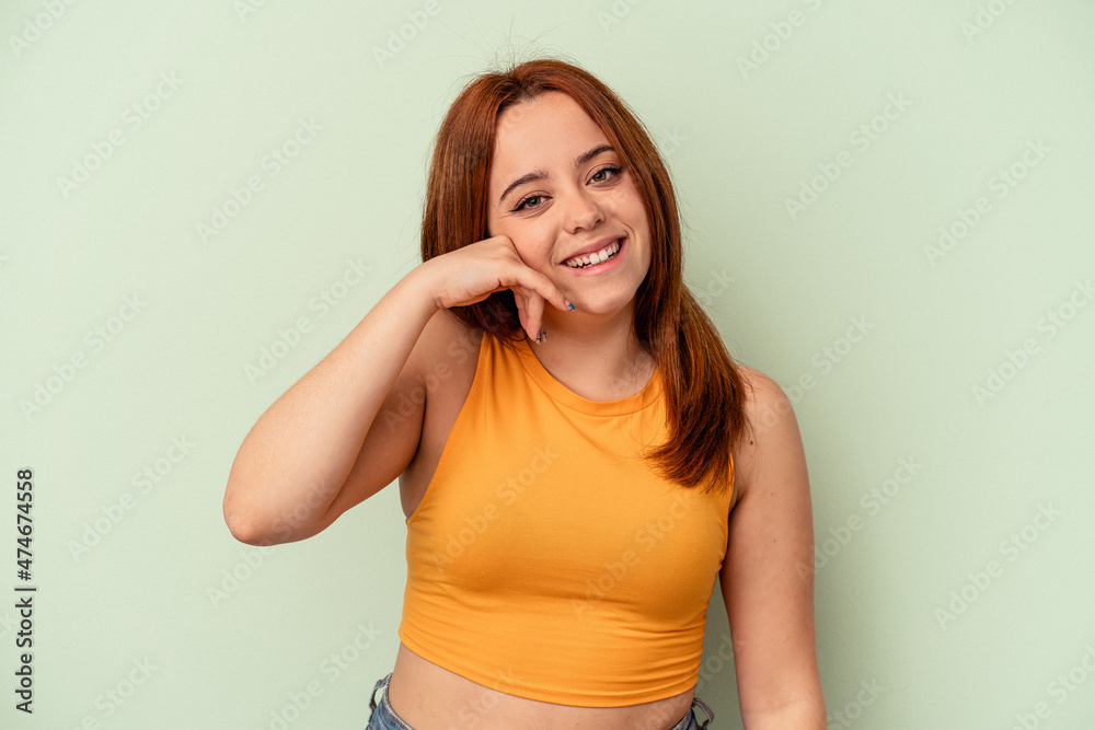 Young caucasian woman isolated on green background showing a mobile phone call gesture with fingers. Young caucasian woman isolated on green background showing a mobile phone call gesture with fingers.